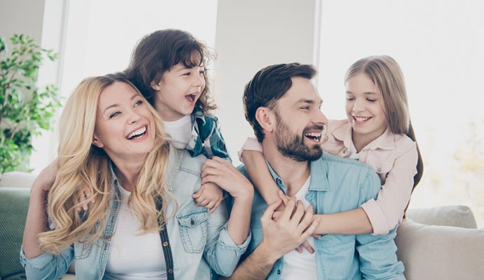 A happy family of four laughing and hugging together